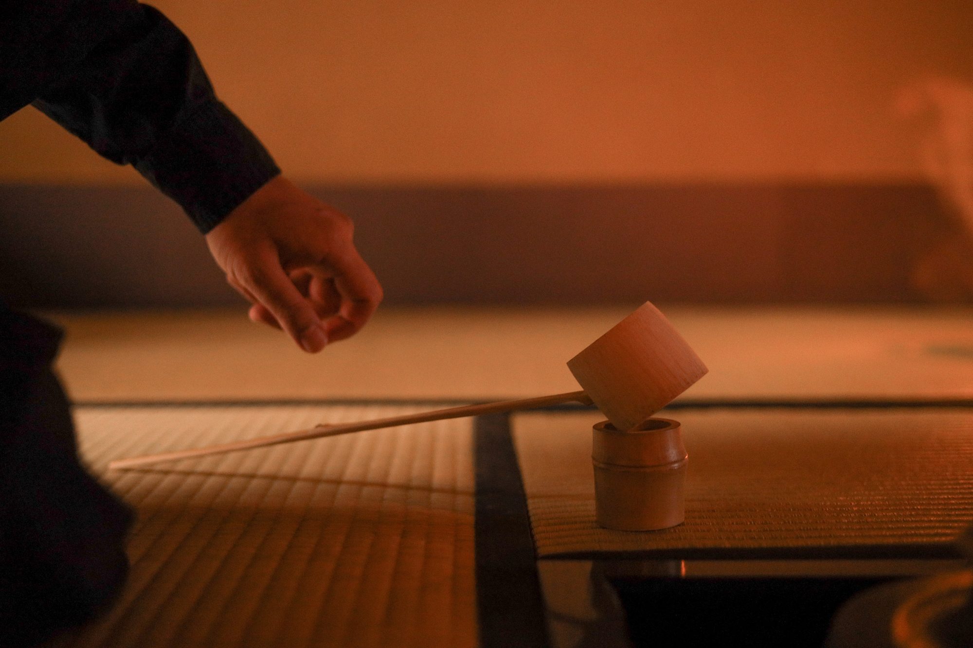 A bamboo ladle resting on its stand in warm light